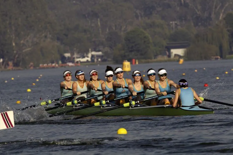 Un gruppo di studenti e studentesse della Geelong Grammar School rema su uno specchio d'acqua davanti a un paesaggio boscoso.