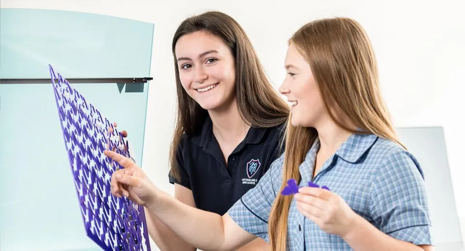 Due studentesse sono davanti a una lavagna bianca e lavorano insieme nel campus della Mitcham Girls High School.