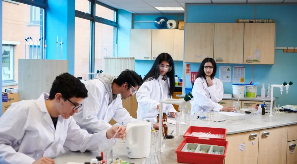 Studenti dell'Abbey College Manchester lavorano insieme in un laboratorio scientifico ben attrezzato.