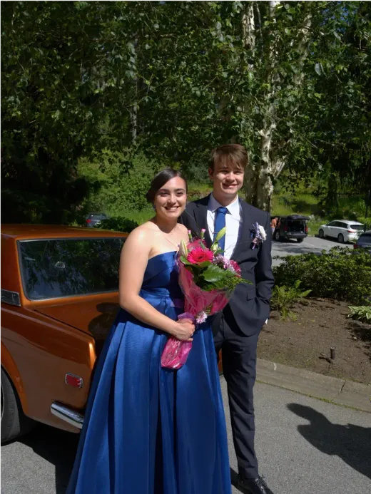 Festlich gekleidetes Schülerpaar mit Blumenstrauß vor dem Schulball in Kanada