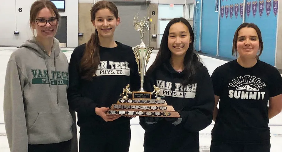 Quattro studentesse con magliette Van Tech Phys Ed della Vancouver Technical Secondary School tengono insieme una coppa.