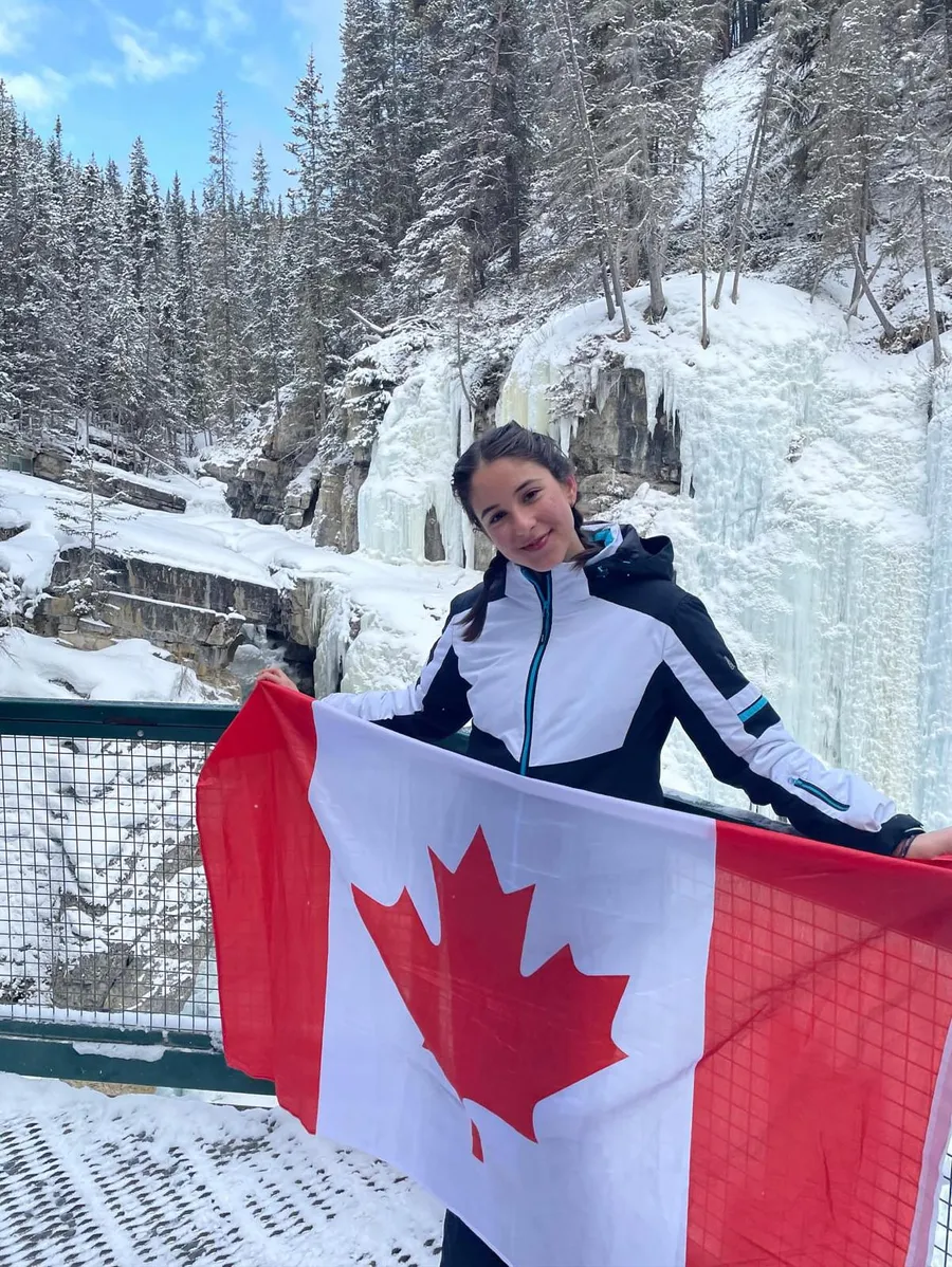 Studentessa con la bandiera del Canada davanti a una cascata ghiacciata