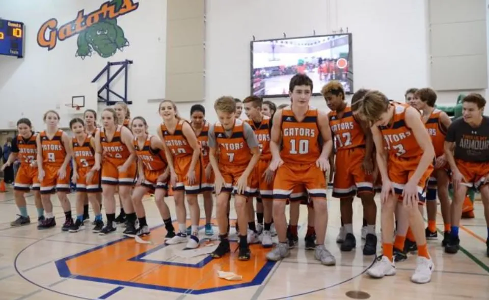 Un gruppo di giovani giocatori e giocatrici di pallacanestro della Lethbridge School Division è riunito in una palestra.