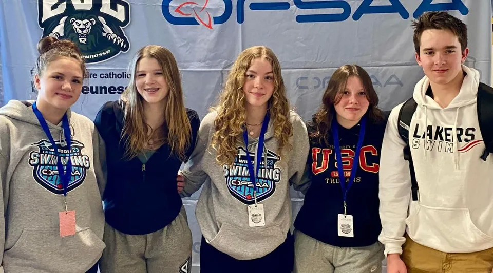 Un gruppo di studenti della Bracebridge and Muskoka Lakes Secondary School sta davanti a uno striscione con il logo di un'organizzazione sportiva.