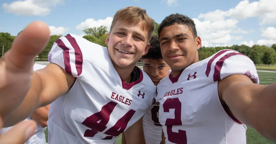 Tre studenti della Indiana Private Highschool indossano maglie sportive bianche e bordeaux e mettono in posa all'aperto davanti a un cielo nuvoloso e alberi.
