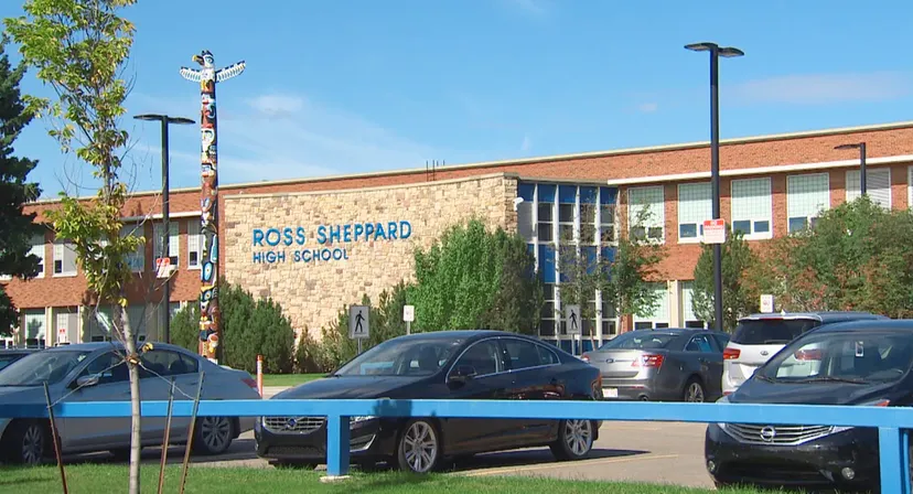 L'edificio in mattoni della Ross Sheppard High School con il nome della scuola sulla facciata e auto parcheggiate davanti.