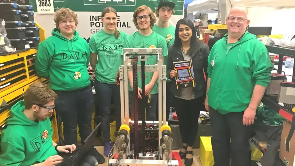 Un gruppo di studenti della St. David Catholic Secondary School si trova davanti a un grande striscione verde con la scritta FIRST ROBOTICS COMPETITION.