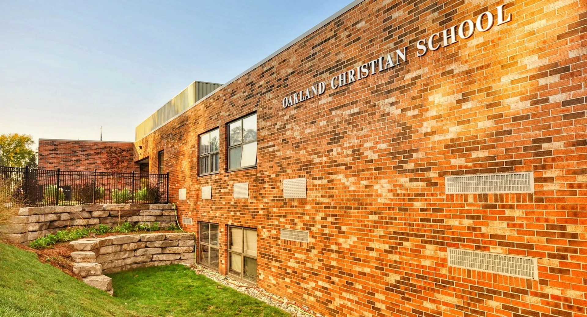 L'edificio in mattoni della Oakland Christian School è circondato da un'area verde e da scalinate in pietra verso l'ingresso.