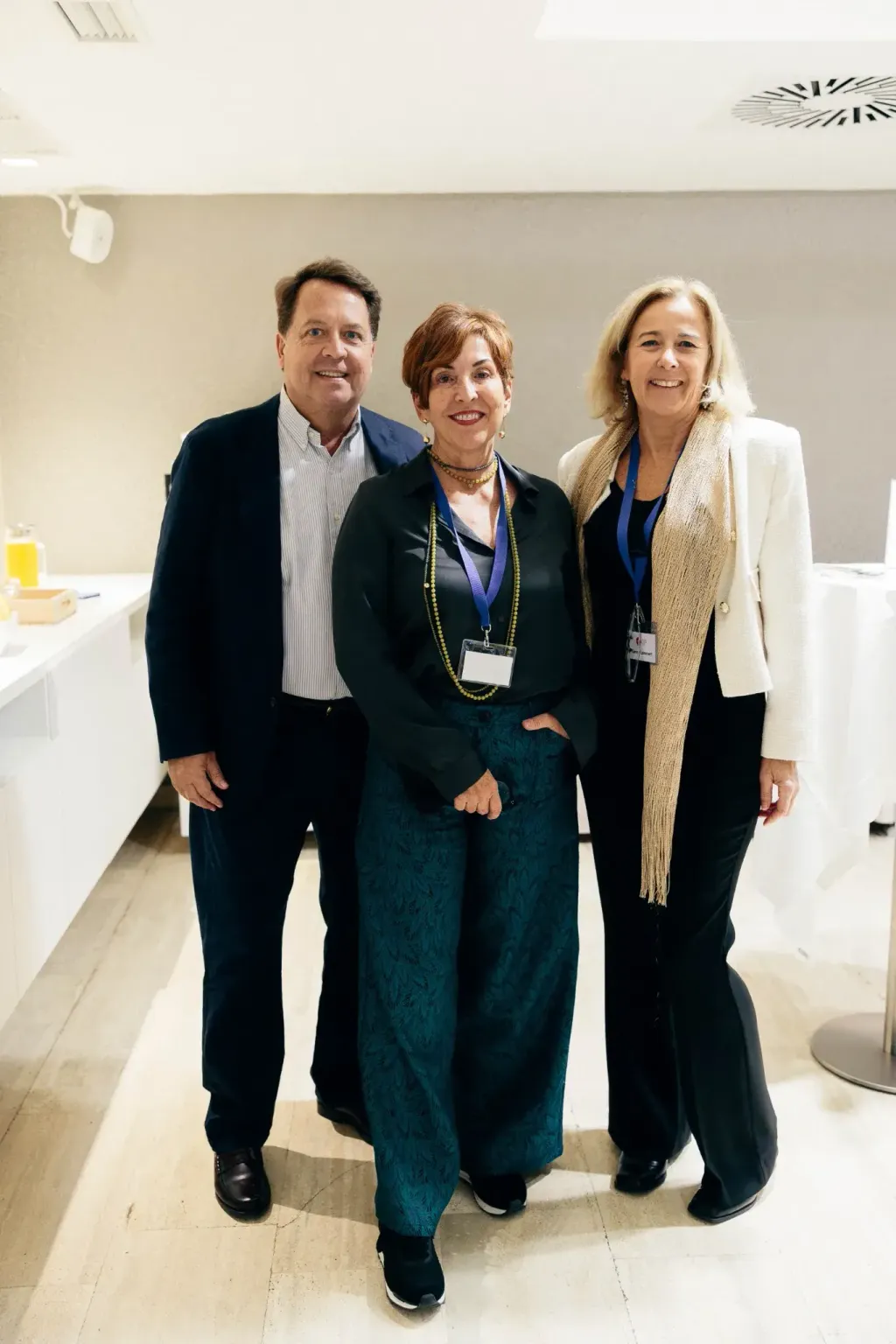 Tres asistentes con acreditación posando durante la recepción del evento
