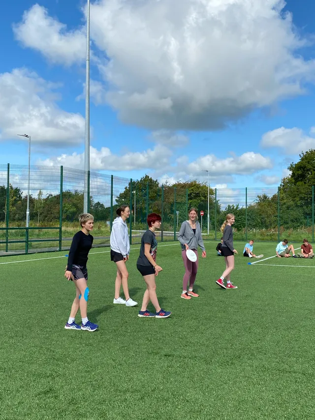 Alumnas jugando al frisbi en un campo de césped artificial del colegio