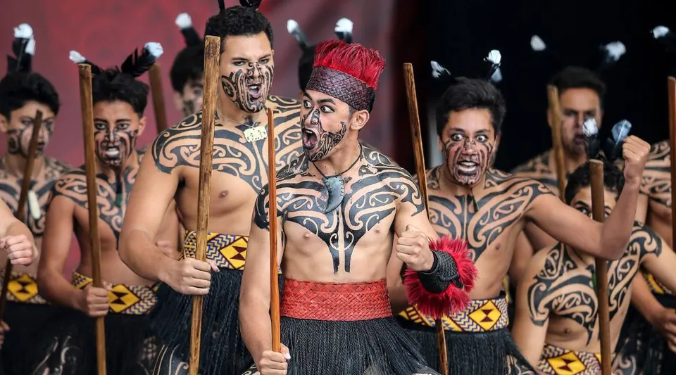 Un gruppo con complessi dipinti corporali e abiti tradizionali durante una performance artistica al King's College.