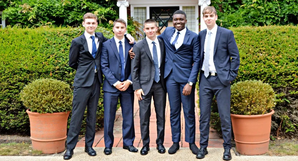 Un gruppo di studenti della Luckley House School si trova in un giardino ben curato con vasi e siepi.