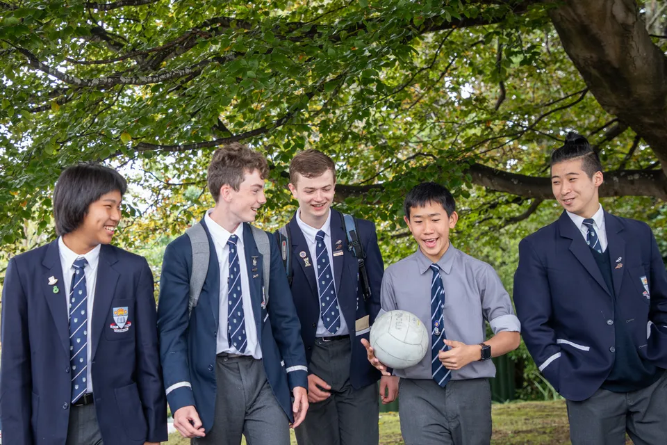 Un gruppo di studenti della Otago Boys' High School si trova insieme in un'area verde all'aperto.