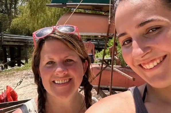 Dos mujeres sonrientes se hacen un selfie al aire libre cerca de unas canoas
