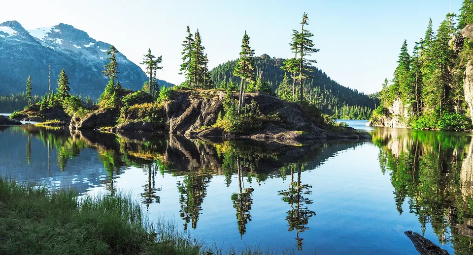 Un calmo lago alpino con montagne e foreste di conifere si riflette nel terreno della Sir Winston Churchill Secondary School.