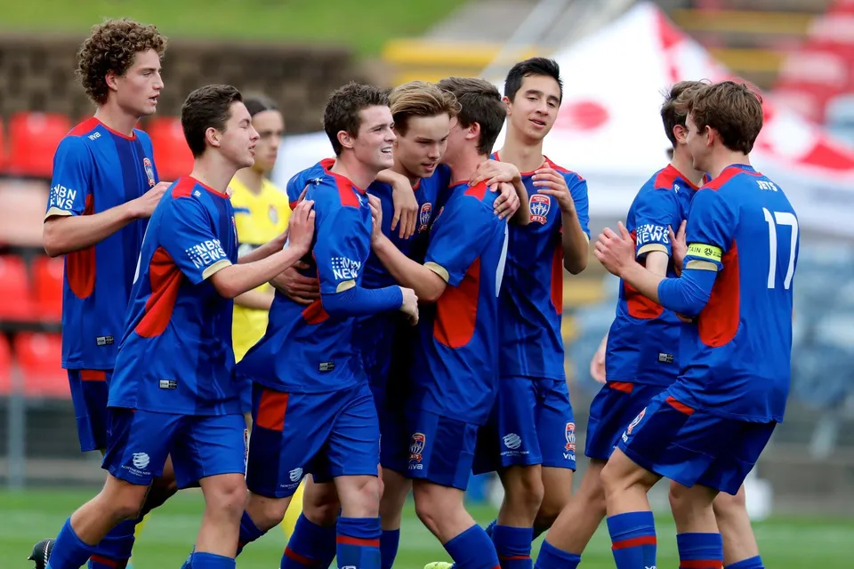 Gli studenti della Newcastle High School insieme sul campo da calcio con la maglia blu.