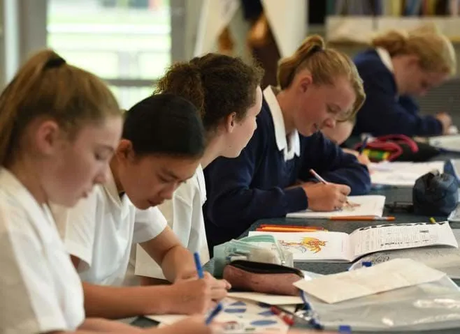 Alumnas de Timaru Girls School se concentran en su trabajo con libros y papeles sobre las mesas.