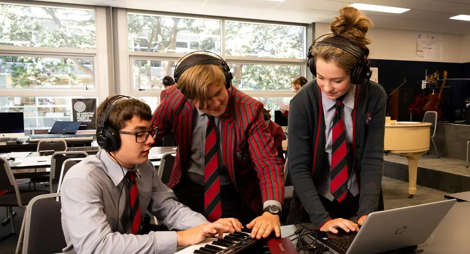Studenti del Scots College lavorano insieme a un laptop in un'aula con grandi finestre.