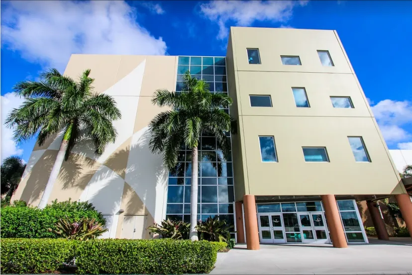 L'edificio a più piani della Calvary Christian Academy è circondato da palme tropicali e si trova sotto un cielo blu limpido.
