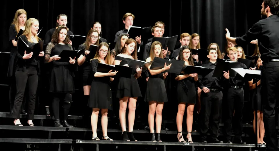 Studenti e studentesse della Rosemount High School cantano insieme su un palco.