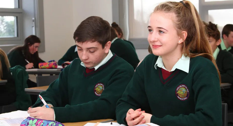 Due studenti in divisa scolastica seduti in un'aula del campus del Castleblayney College.