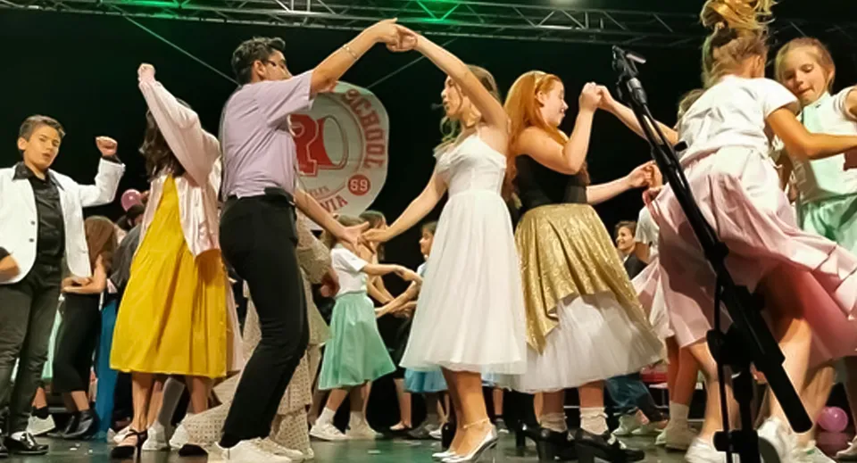 Un gruppo di studenti festeggia insieme sul palco del Sage College con le braccia alzate.