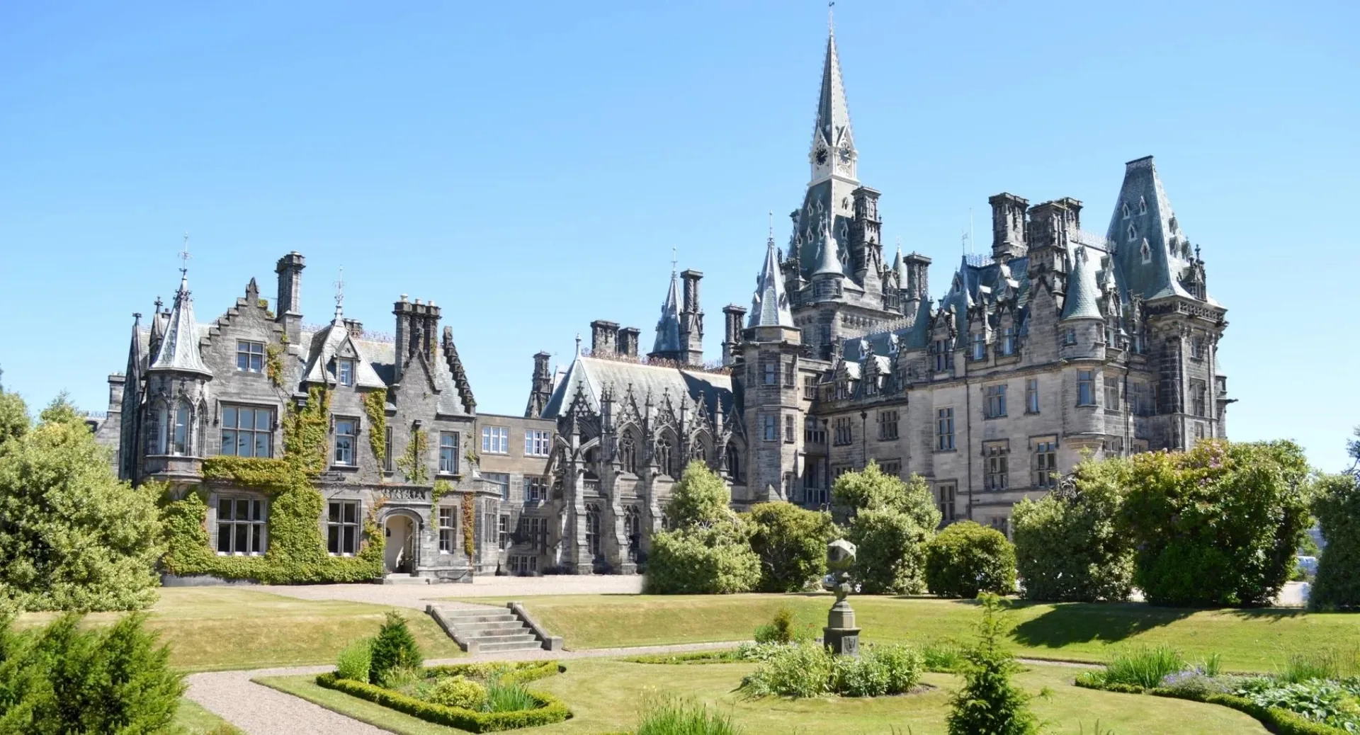 L'edificio storico in pietra del Fettes College con numerose torri e un giardino ben curato in primo piano.
