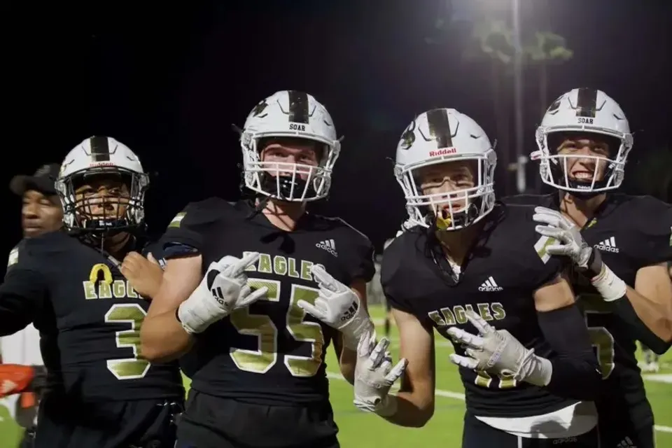 Un gruppo di giocatori di football in divisa si trova sul campo da gioco sotto i riflettori accesi nel campus dell'Oak Park Unified School District.
