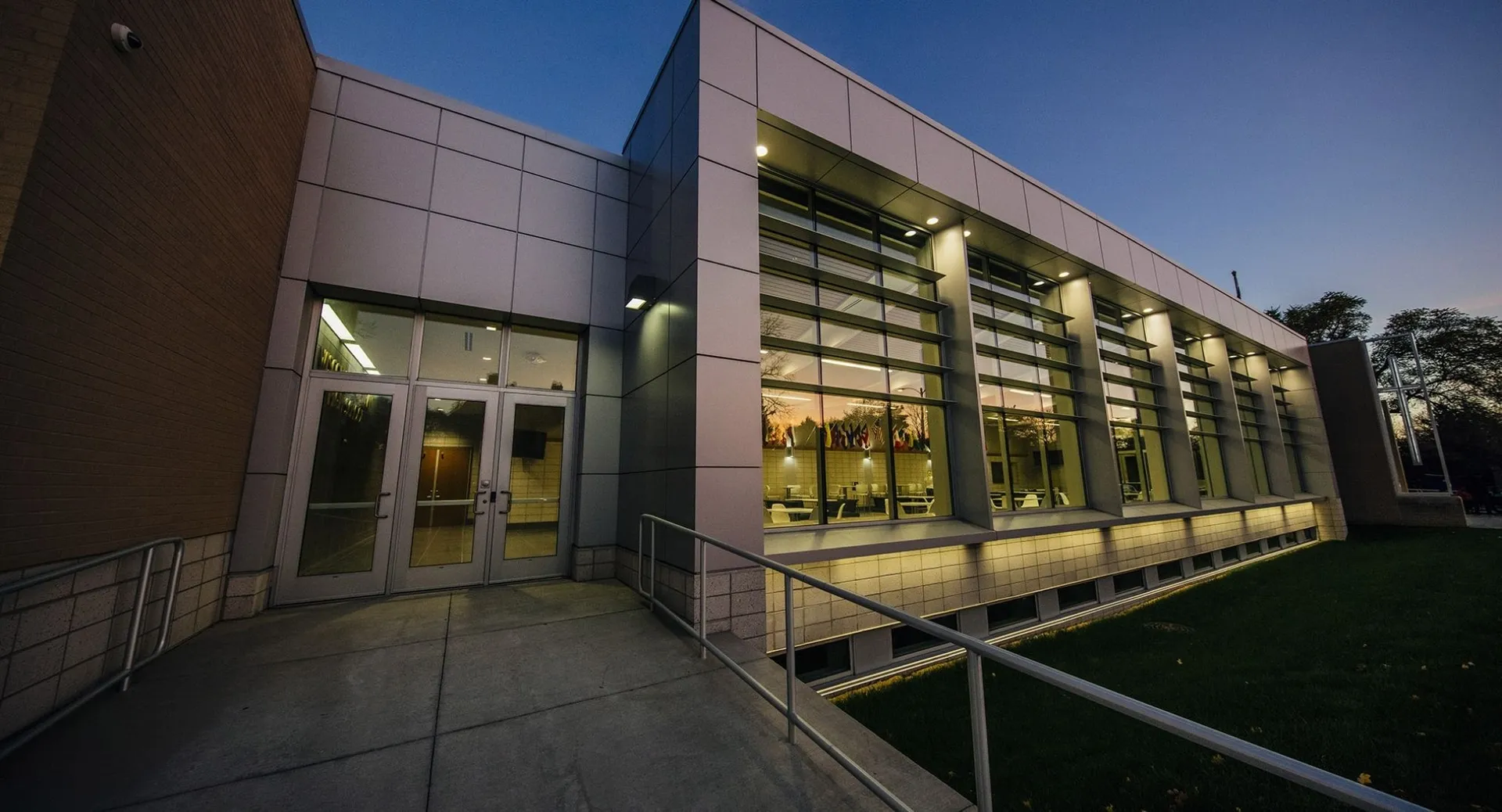 L'edificio moderno a più piani della Northeastern Wisconsin Lutheran High School con pareti in vetro si erge illuminato su un prato.