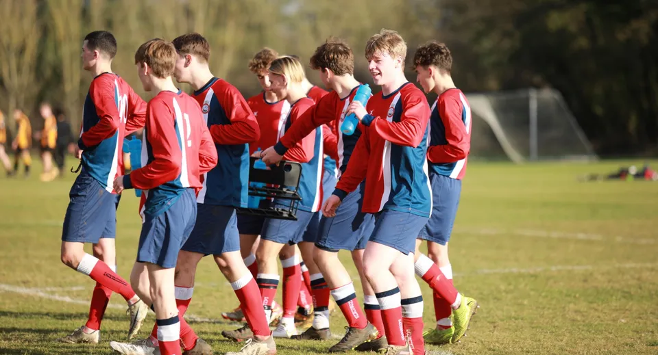 Un gruppo di giovani calciatori è radunato sul campo sportivo del Pangbourne College.
