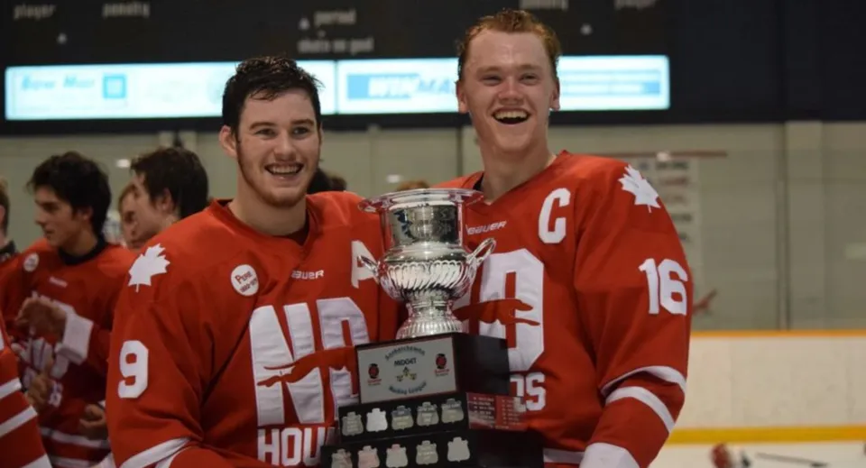 Due giocatori di hockey su ghiaccio dell'Athol Murray College of Notre Dame festeggiano la loro vittoria con una coppa sul ghiaccio.
