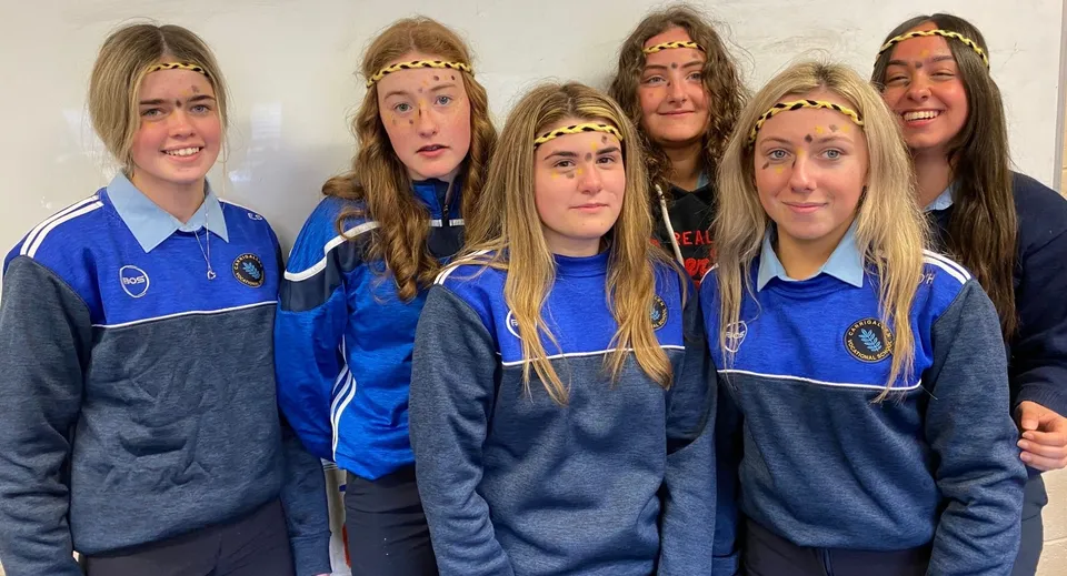 Un gruppo di studenti della Carrigallen Vocational School indossa divise blu e posa insieme con diverse espressioni del viso.