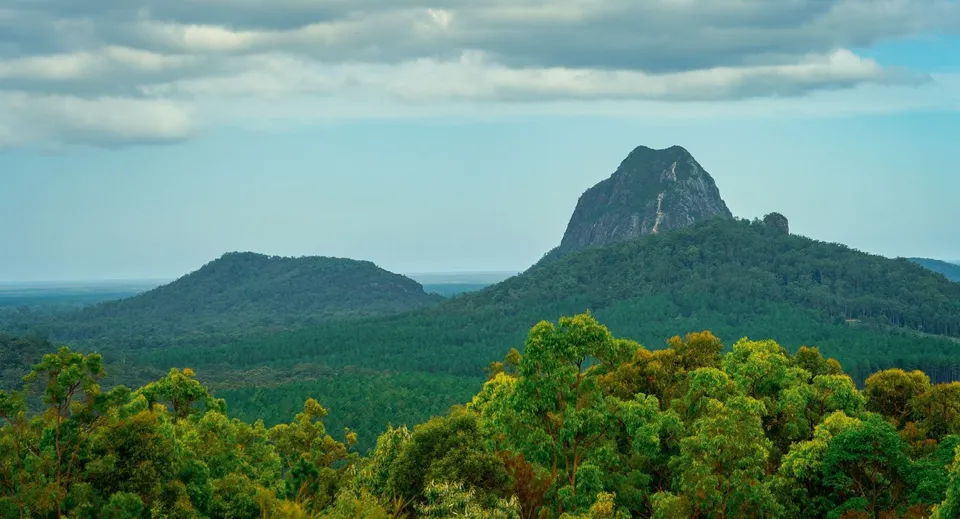 Il paesaggio naturale con boschi verdi e caratteristiche formazioni rocciose vicino alla Burnie High School sotto un cielo nuvoloso.