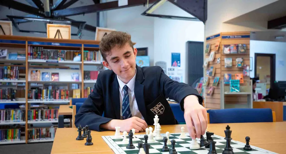 Uno studente della Warwick School si concentra su una partita a scacchi in biblioteca.