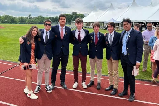 Aitana y sus compañeros de internado, con blazer y corbata, posan en la pista de atletismo