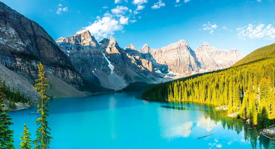 Un tranquillo lago turchese circondato da montagne innevate e verdi foreste vicino alla Robert Thirsk High School.