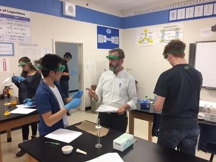 Un profesor y estudiantes de la Fredericton Christian Academy realizan un experimento con gafas de protección en el laboratorio.