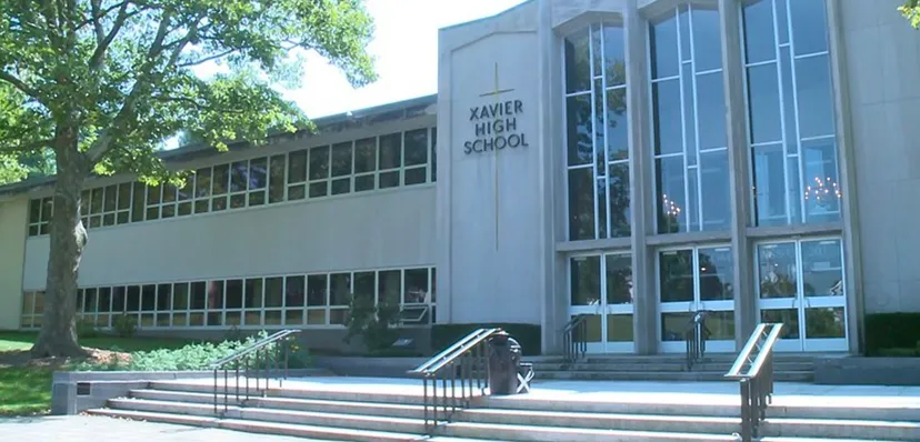 Si vede l'edificio scolastico della Xavier High School con grandi finestre e un ingresso circondato da aree verdi.