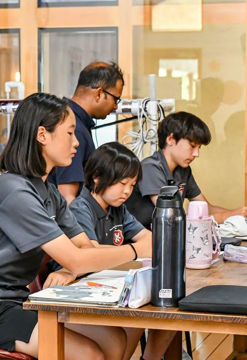 Drei Schüler der Ascot International School sitzen an einem Tisch und schauen auf ihre Unterlagen.