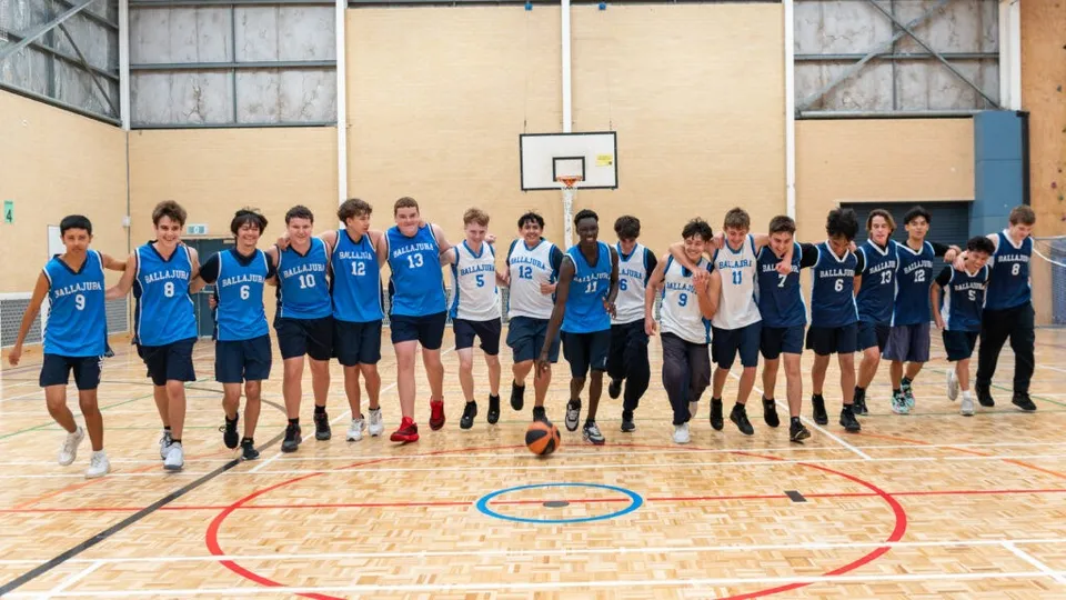 Un gruppo di studenti gioca a basket sul campo sportivo del Ballajura Community College.