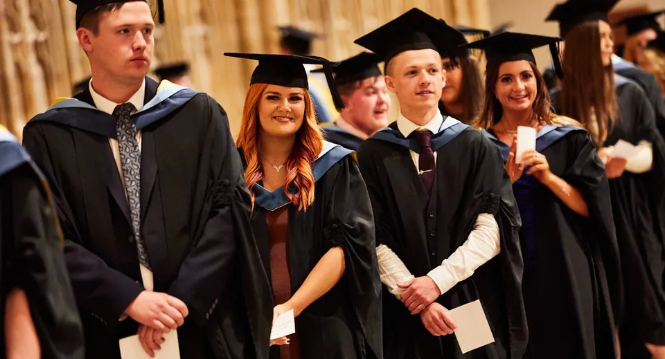 Un gruppo di diplomati in abito accademico si trova insieme alla cerimonia di diploma del Queen Ethelburga’s Collegiate.