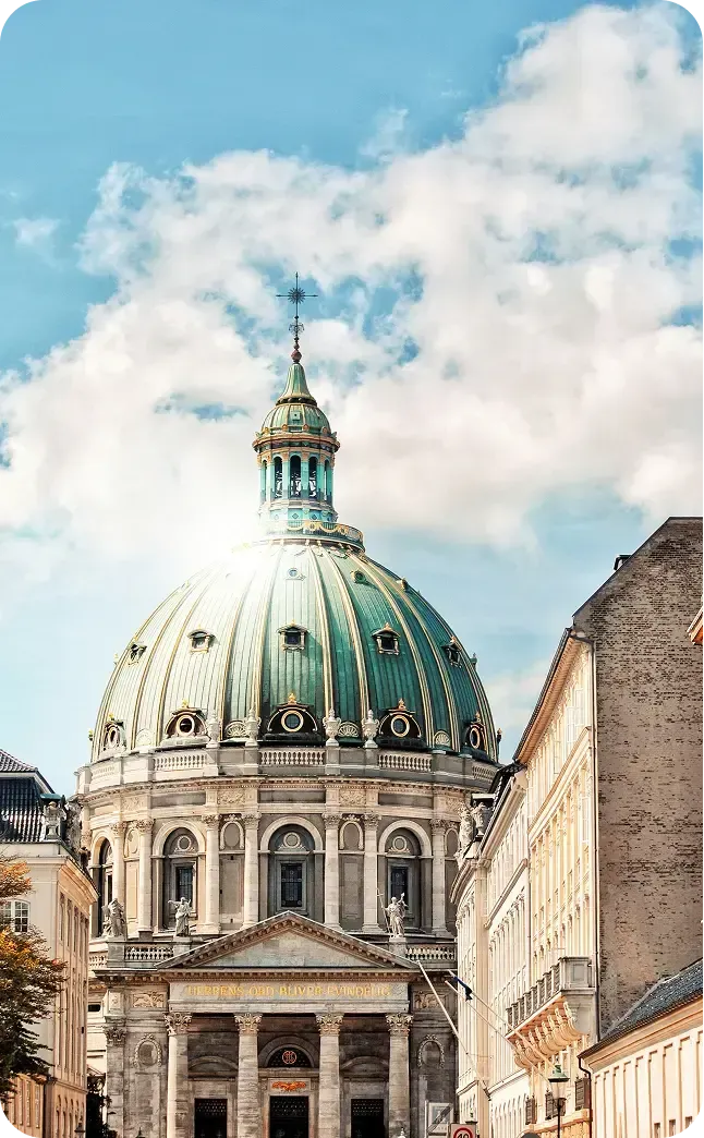 Grande cupola verde in rame di una chiesa storica sotto un cielo azzurro con nuvole