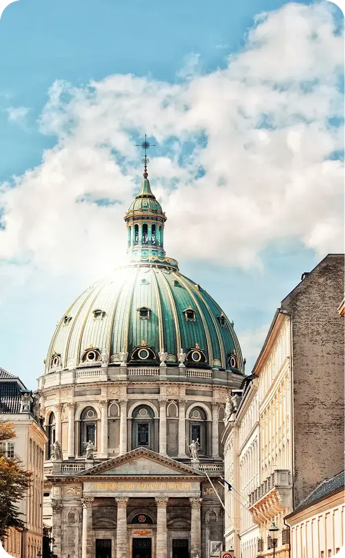 Grande cupola verde in rame di una chiesa storica sotto un cielo azzurro con nuvole