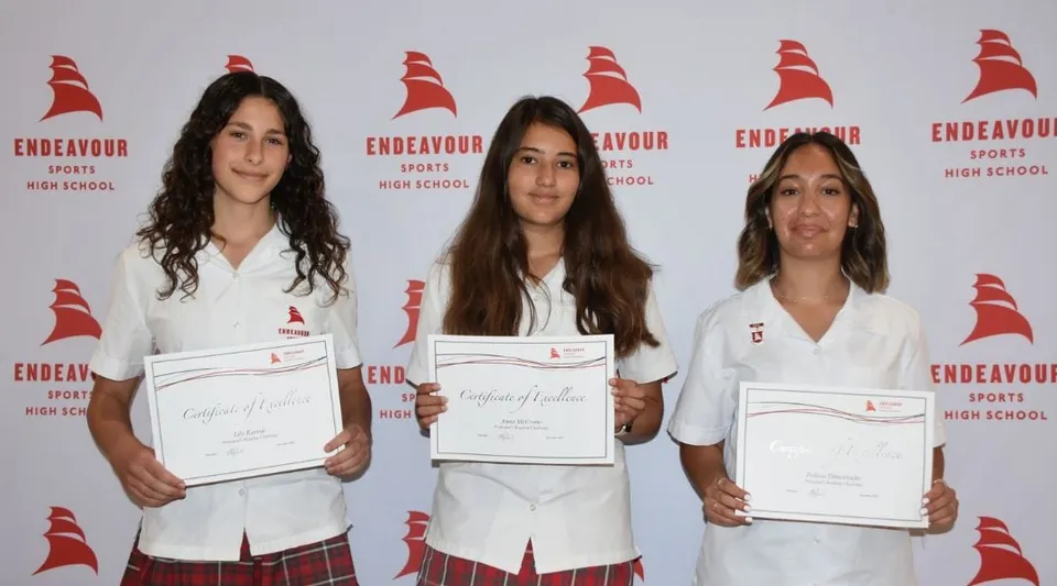 Tre studentesse della Endeavour Sports High School mostrano i loro certificati davanti a uno sfondo con logo.