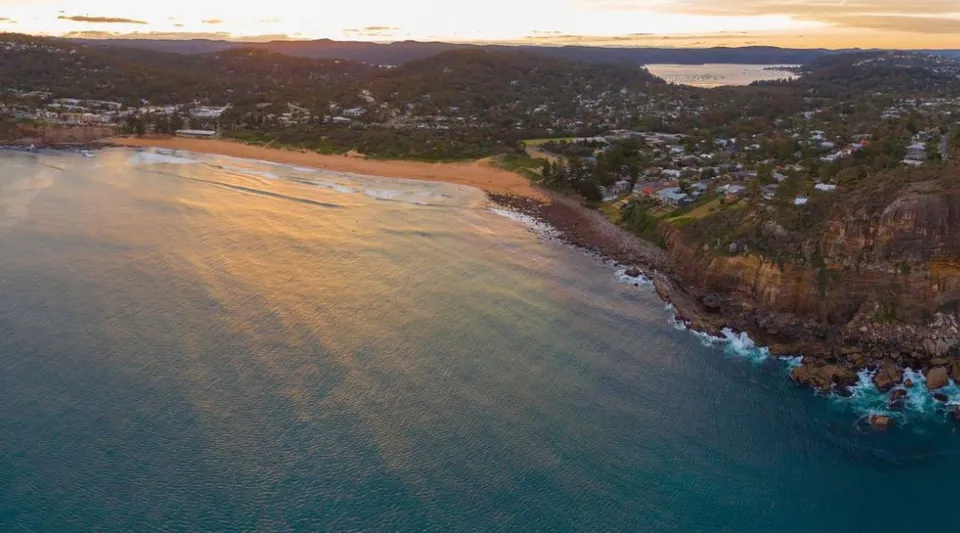 Vista aerea di una città costiera con colline verdi e mare turchese vicino alla Barrenjoey High School.