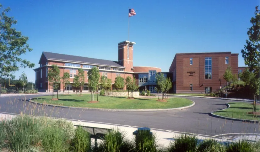 Un edificio in mattoni rossi con un grande pennone si erge sul prato ben curato della Marblehead High School.