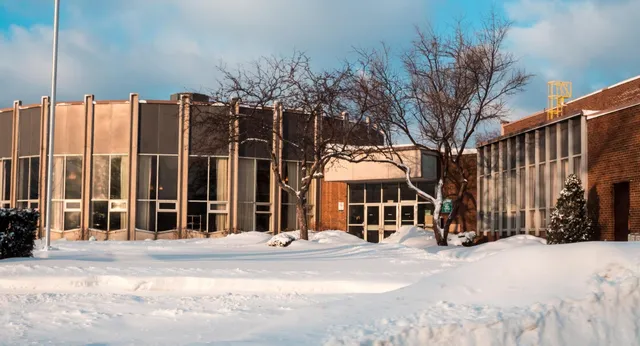 Das verschneite Backsteingebäude der Westview Freedom Academy steht vor kahlen Bäumen unter einem bewölkten blauen Himmel.