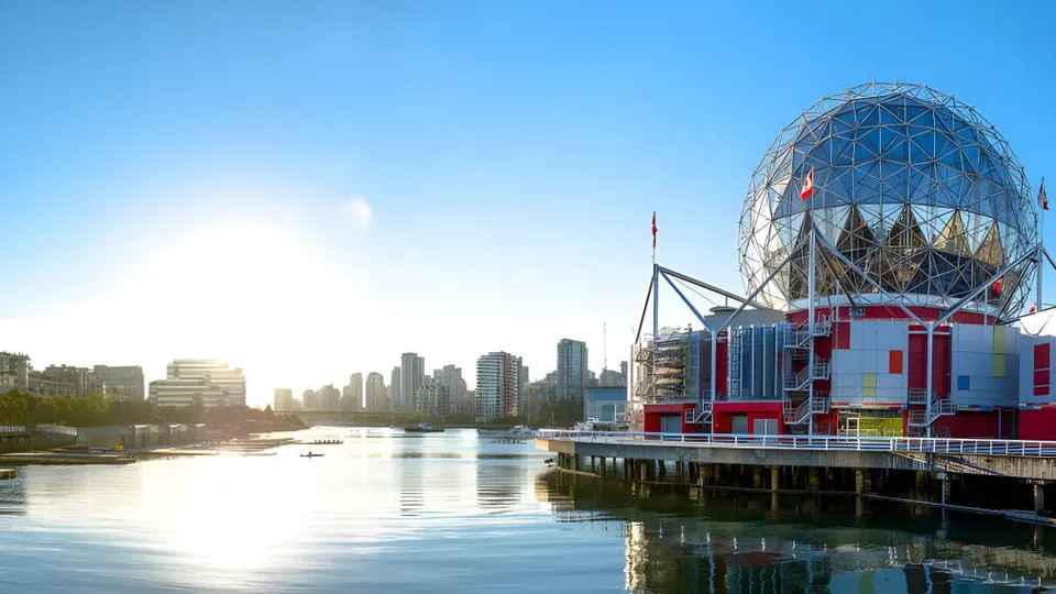 Una gran cúpula geodésica de cristal en la orilla con el horizonte de la ciudad de fondo y sol.
