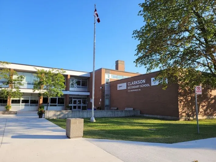 Die Clarkson Secondary School ist umgeben von Bäumen und vor dem Eingang ist eine kanadische Flagge zu sehen.