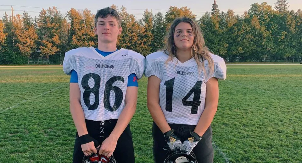 Due studenti del Collingwood Collegiate Institute si trovano in maglia sportiva su un prato con un bosco sullo sfondo.